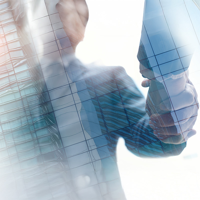 Two people shaking hands as a sign of agreement or collaboration, superimposed on a modern glass building with reflections, creating a transparent and professional superimposed effect.