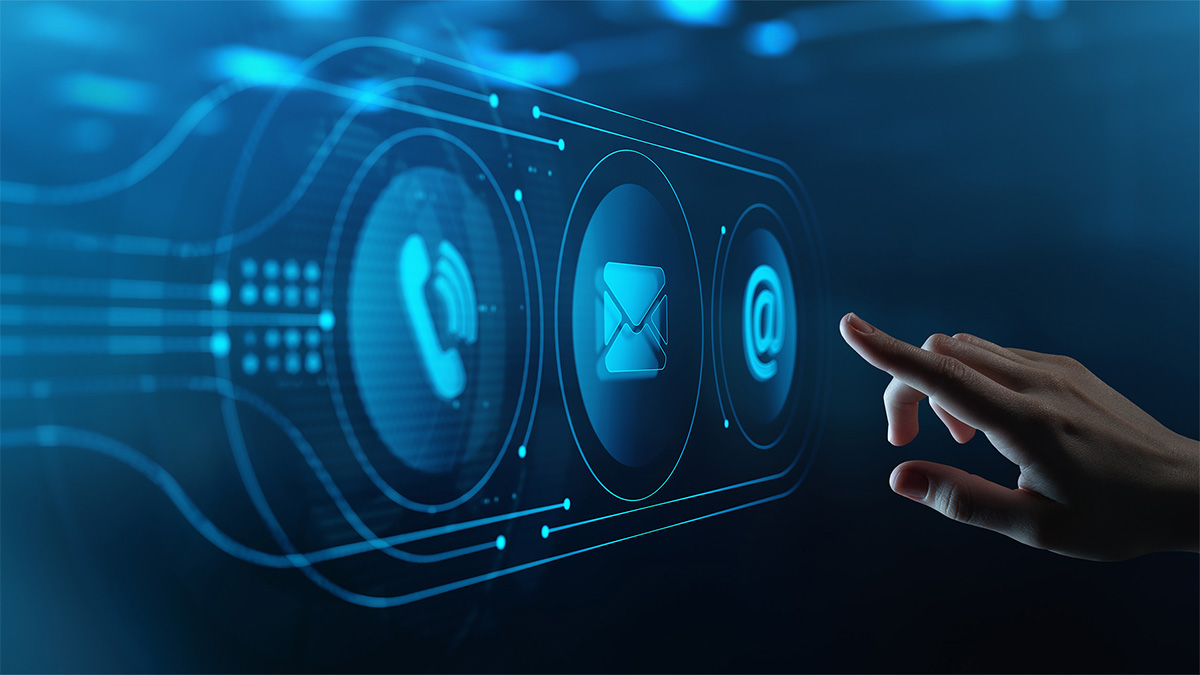 Due persone sedute a un tavolo, viste di profilo, che discutono e collaborano davanti a un dispositivo portatile (come un laptop o tablet). Sul tavolo si intravede materiale di lavoro (appunti, tazze, documenti), e sullo sfondo si percepisce un ambiente professionale luminoso e moderno